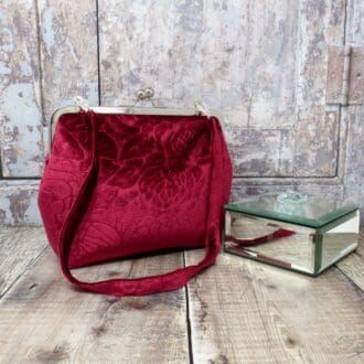 A handmade red velvet evening bag set into a silver kiss lock frame and with a removable velvet handle.
