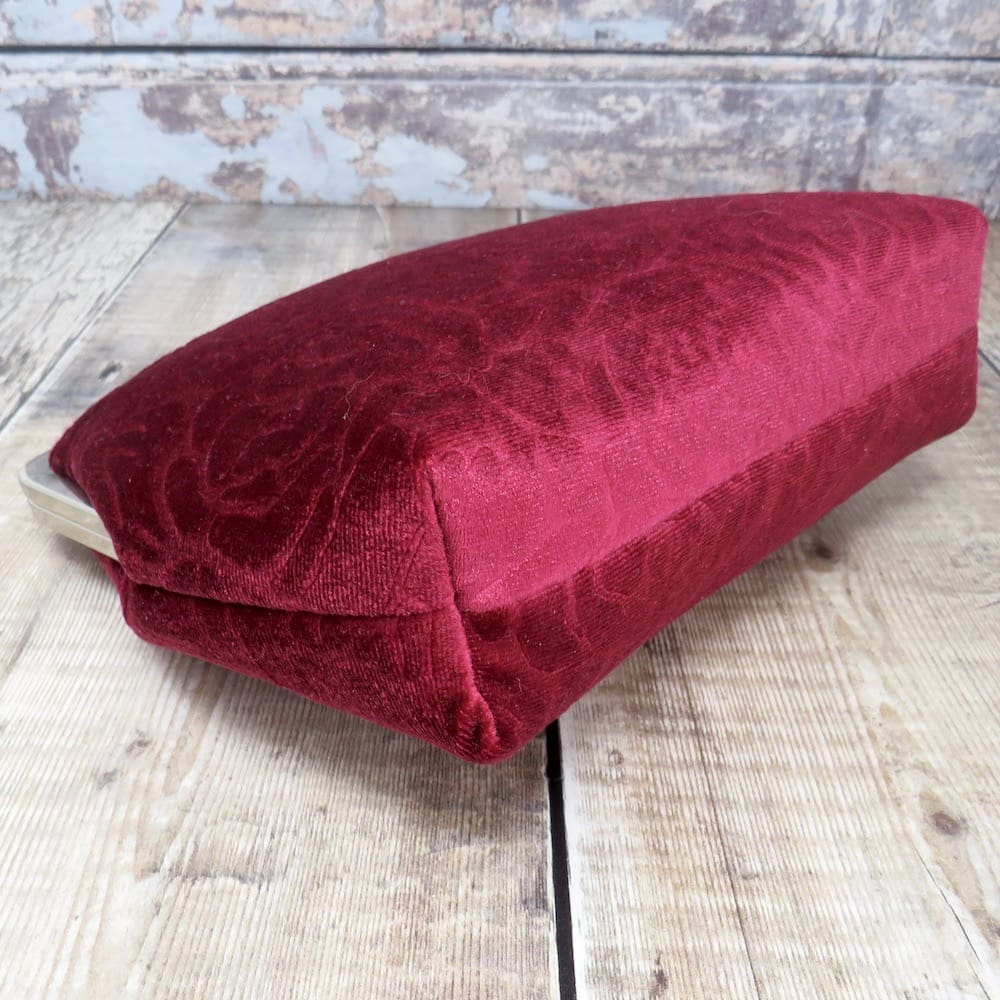 A handmade red velvet evening bag set into a silver kiss lock frame and with a removable velvet handle.