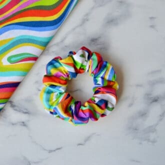 Retro rainbow scrunchy. fabric has wavy lines of blue, yellow, red, pink, green and white