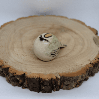 Ceramic gold crest with real gold on crest, sat on a wooden round with a white background