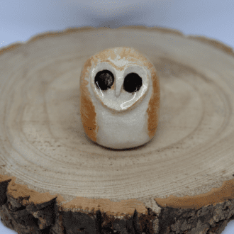 Ceramic barn owl on a wooden round with white background