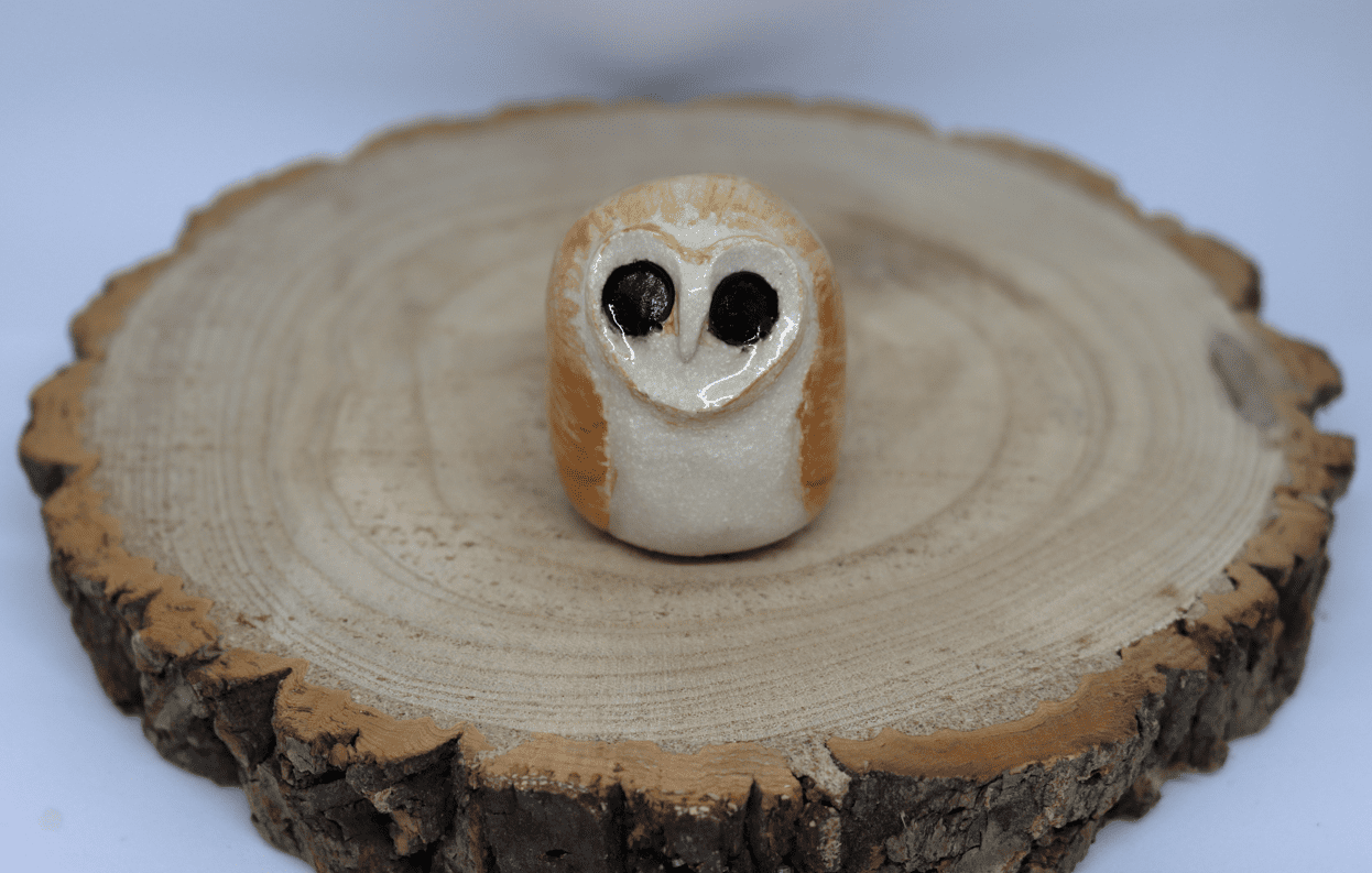 Ceramic barn owl on a wooden round with white background