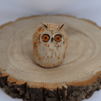 Ceramic long eared owl looking shocked on a wooden round