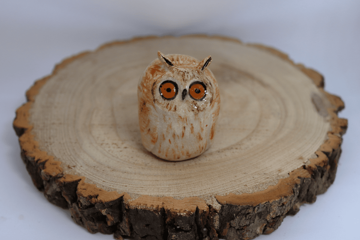 Ceramic long eared owl looking shocked on a wooden round
