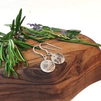 sweet cicily herb imprint drop earrings displayed on a piece of olive wood