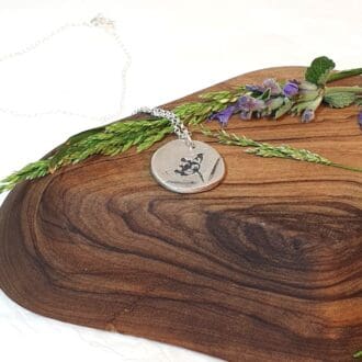 cow parsley imprint pendant displayed with a herb sprig on a wooden block