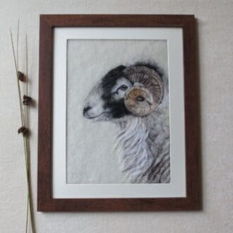 A handmade needle felted wool picture of a Swaledale sheep in a dark brown wood effect frame.