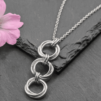 Three large mobius chainmaille units linked together in a pendant made from aluminium rings on a stainless steel chain