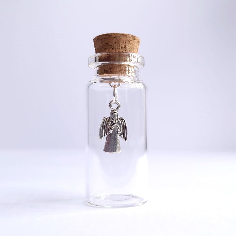 Angel charm keepsake inside a miniature glass bottle by under the blossom tree