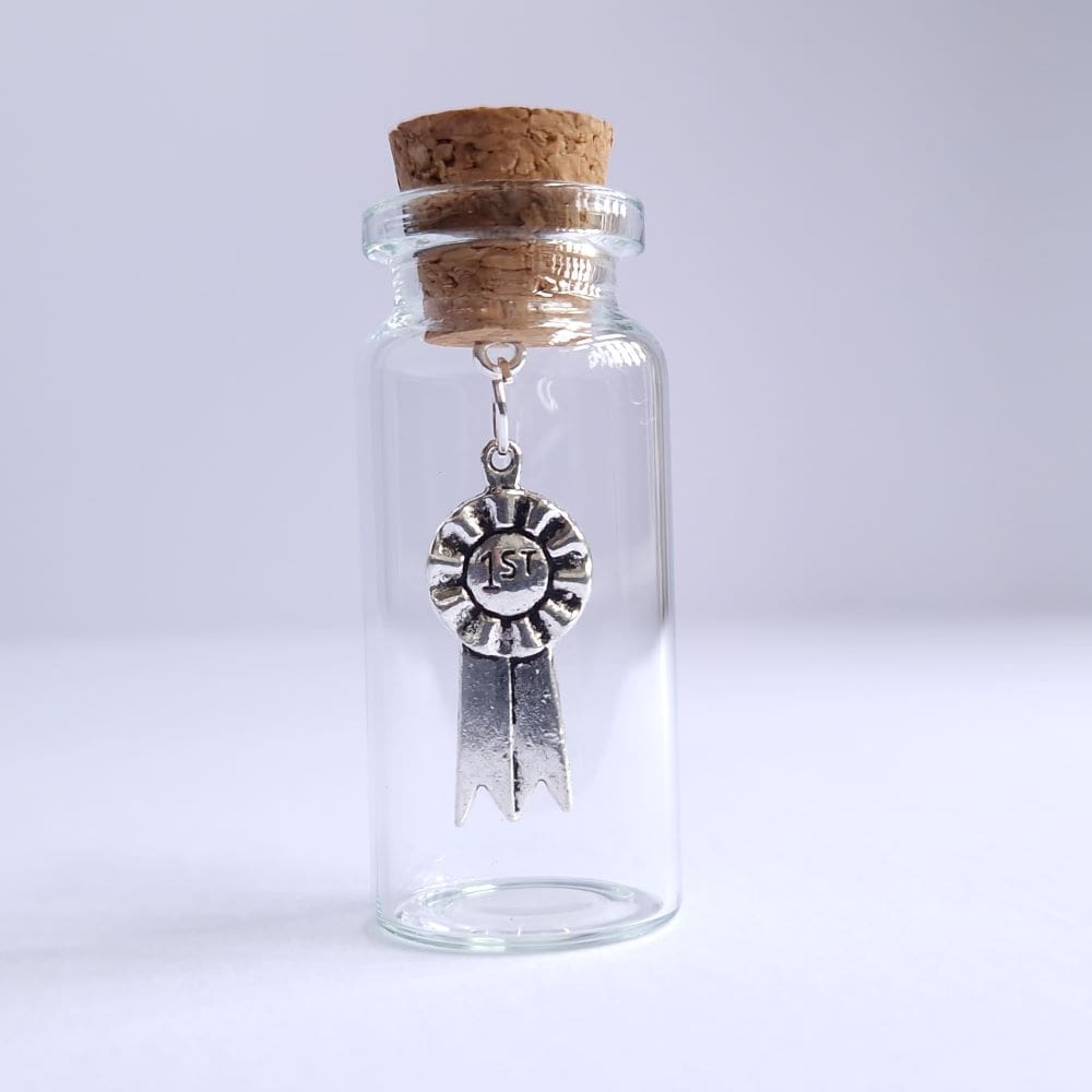 Silver rosette charm in a miniature glass bottle by under the blossom tree