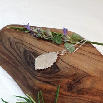 Silver wild rose leaf on an olive wood plinth
