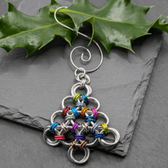 A chainmaille Christmas decoration in the shape of a Christmas tree made from silver and lots of different coloured aluminium rings.