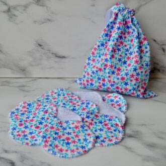 Floral daisy cotton pads with a matching drawstring storage bag. The fabric is white with small pink and blue daisies, and the storage bag features the same floral print.
