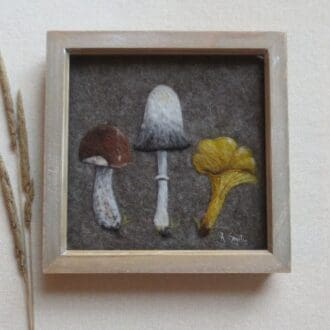 A handmade needle felted wool painting of a brown birch bolete mushroom a shaggy ink cap and a yellow chanterelle in a natural wood box frame.