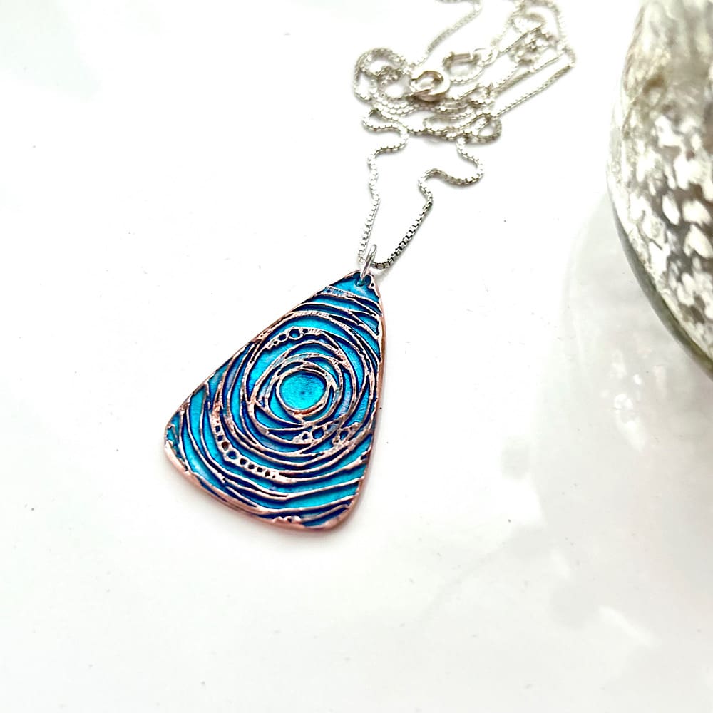 A copper pendant hand painted in turquoise blue with a sterling silver chain.