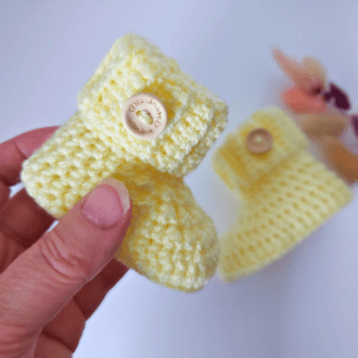 a pair of ready made crochet lemon baby booties for a newborn