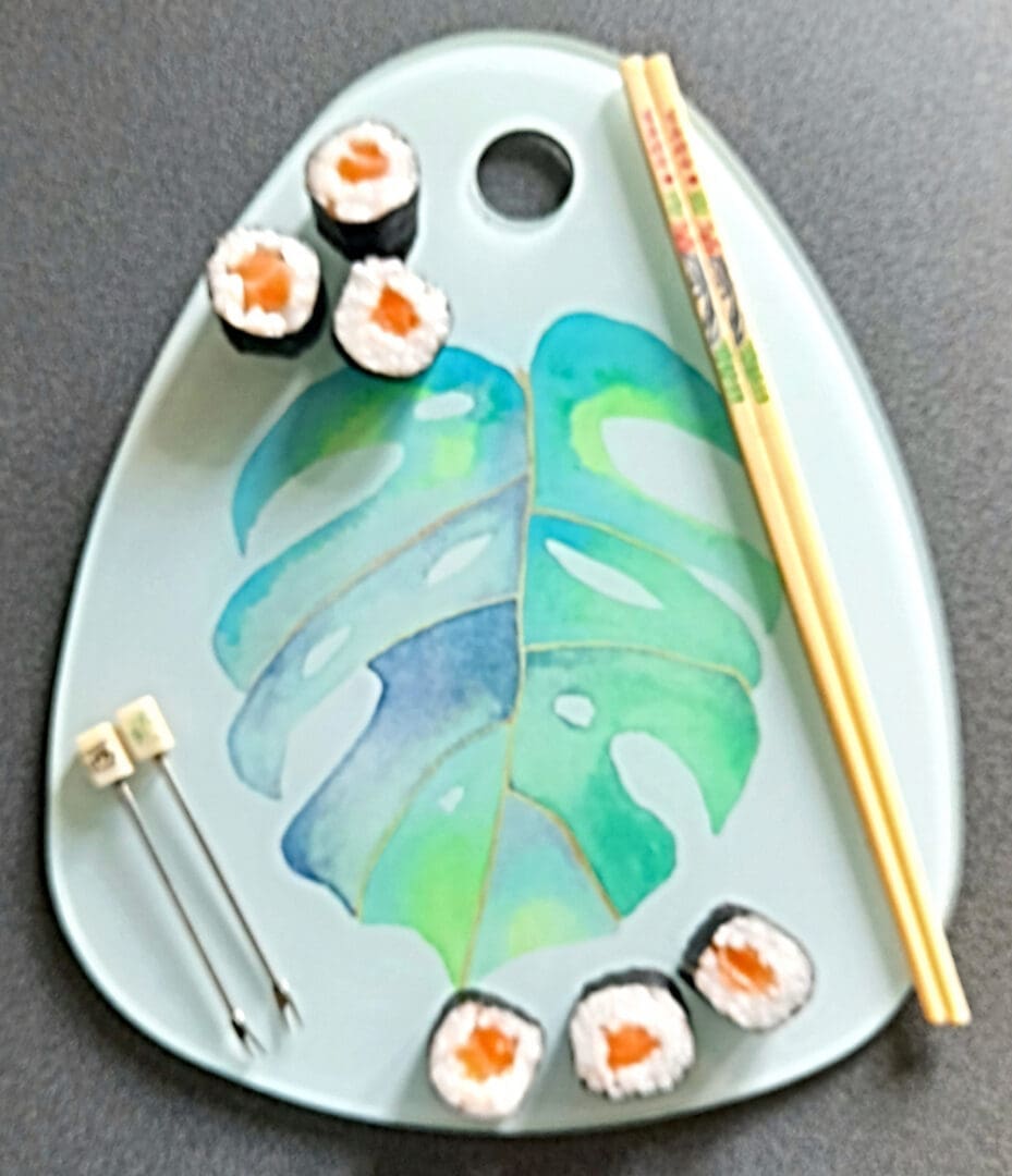 Charcuteri glass board with monstera leaf art displayed with Sushi nibbles