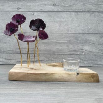 5 resin poppies on gold stems set in a wooden log slice. The poppies are very dark red almost black with glittered finish