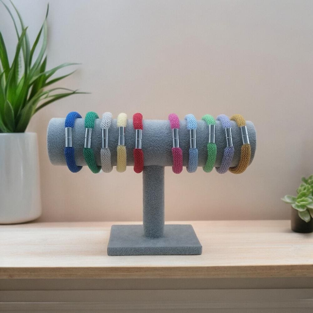 Selection of single chunky colourful stackable bracelets displayed on a stand against a neutral background.