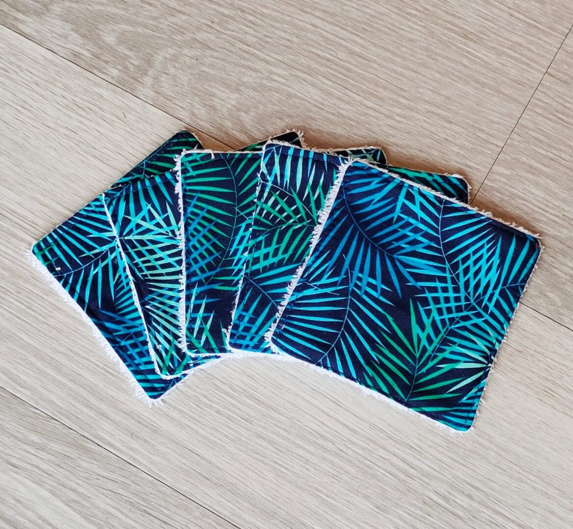 A set of five reusable face wipes with fern leaves on the cotton top fabric.