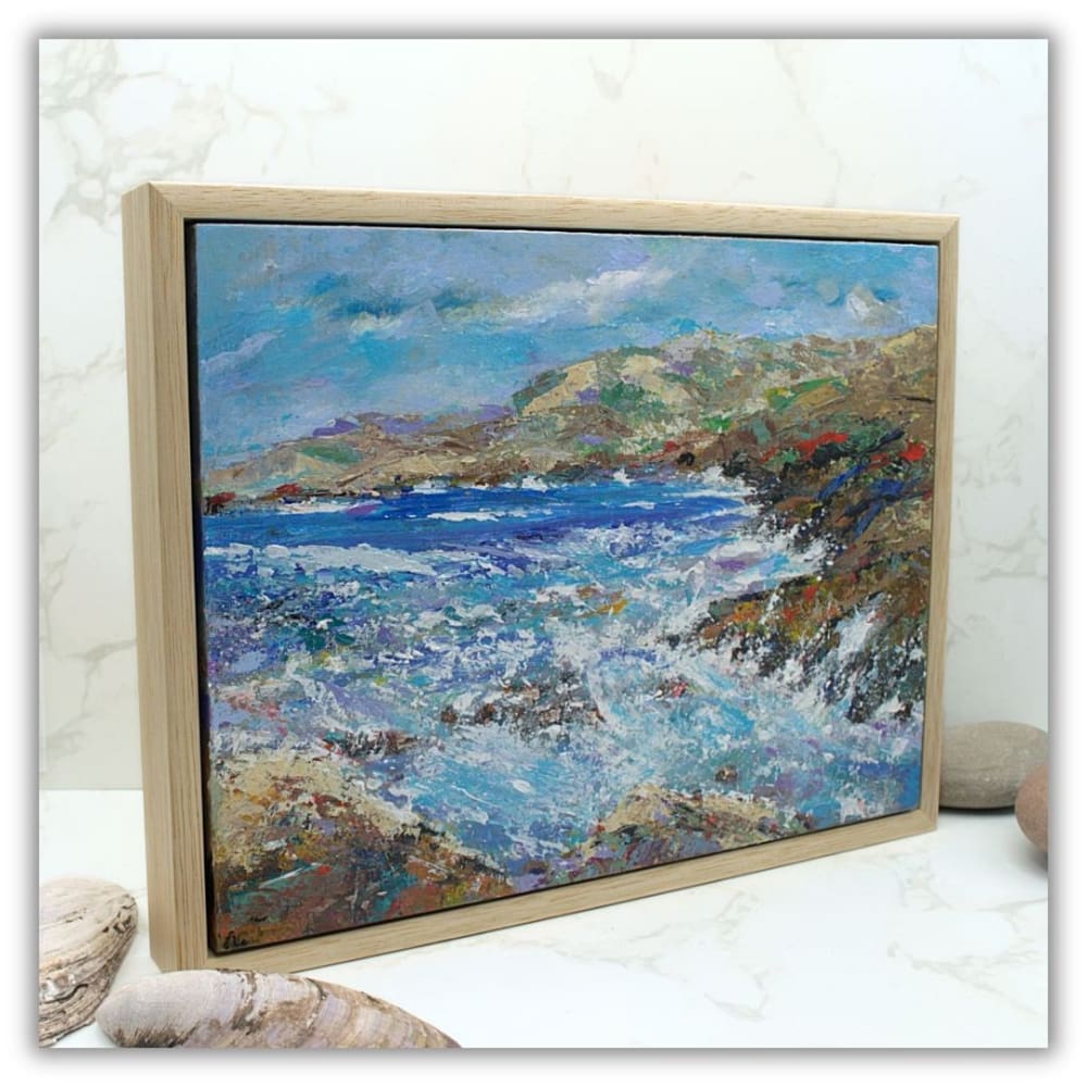 A framed coastal landscape painting.