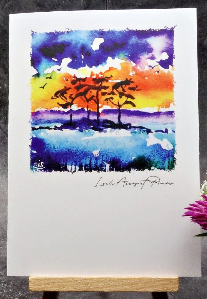 Larger image showing an A6 size greetings card, blank inside, on a small easel displaying an evening view of some of the famous Loch Assynt Pines