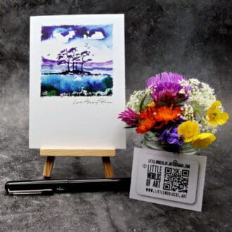 Image showing an A6 size greetings card, blank inside, on a small easel displaying a view of some of the famous Loch Assynt Pines
