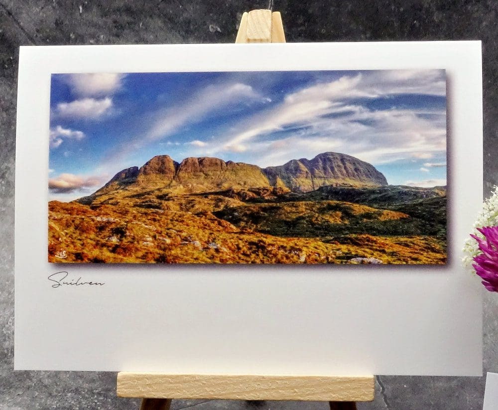 Larger image showing an A6 size greetings card, blank inside, on a small easel displaying an evening view of Suilven's north face.