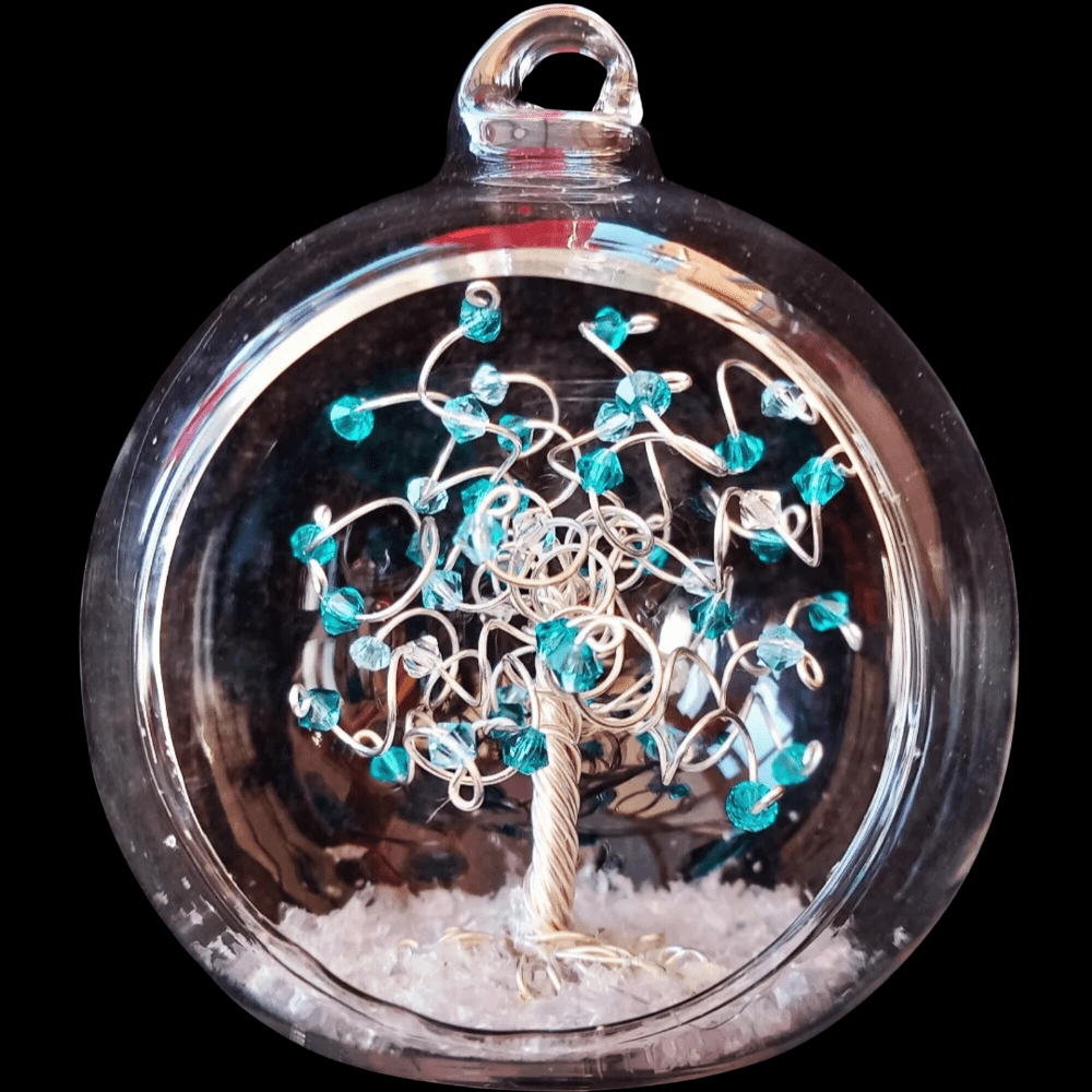 8cm open fronted glass bauble with a silver wire tree set into is on a snowy base. The branches are decorated with blue zircon crystals and aquamarine.