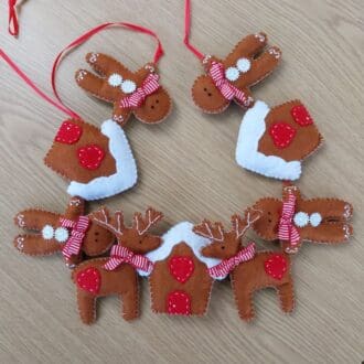 a hand stitched felt christmas garland of gingerbread men, reindeer and gingerbread houses