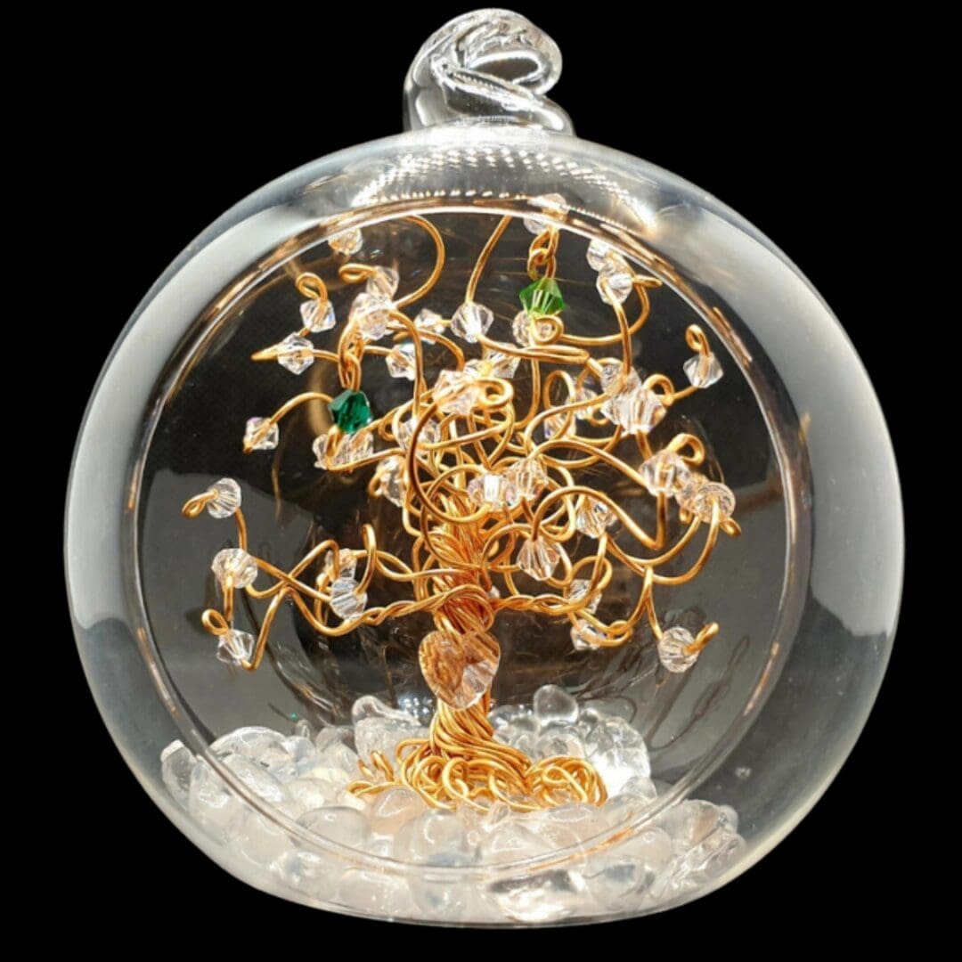 Gold wire tree sitting inside an 8cm glass open fronted bauble. The tree is decorated with clear crystals and birthstones with a crystal heart wired near the roots.