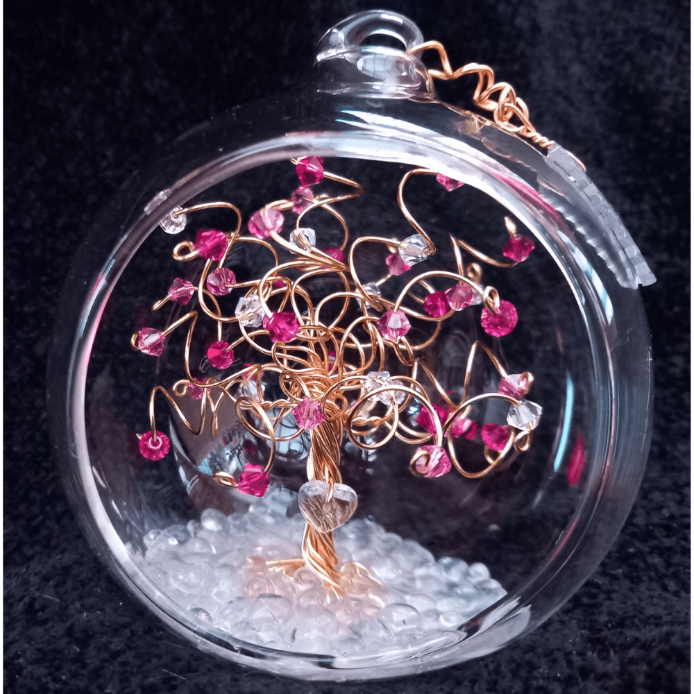 8cm glass bauble open fronted with a miniature gold wire tree with a mix rose and fuschia crystals on the branches, and a clear crystal heart wired into the trunk. It's set into a glass pebble base.