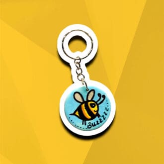 Handmade wooden disc bumblebee keyring on a blue background with the word "buzz".