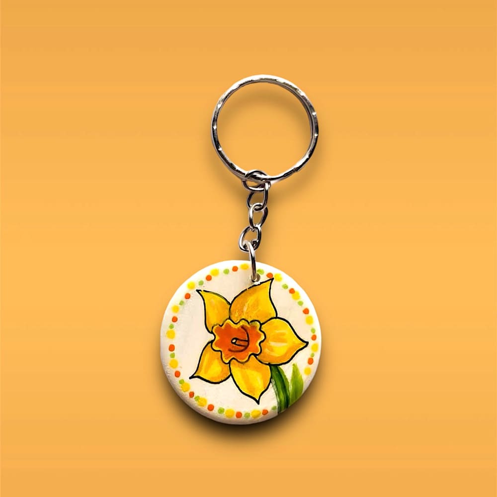 Handmade, hand painted wooden circular daffodil design keyring. Yellow and orange daffodil. Dots around the circles edge.