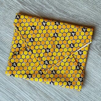 Reusable sandwich wrap with a honeycomb bee cotton outer fabric and food-safe PUL lining.