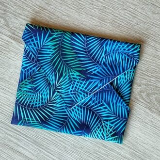 Reusable sandwich wrap approximately 30cm square, with a green and blue fern print cotton outer and food safe PUL lining.