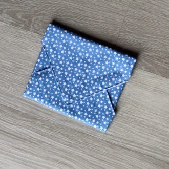 Reusable sandwich wrap with small white stars on light blue cotton outer fabric and food-safe PUL lining.