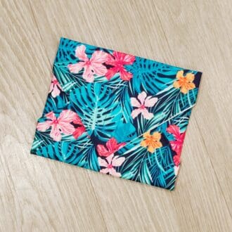 Reusable sandwich wrap with tropical flowers and leaves on a navy blue cotton outer fabric and food-safe PUL lining.