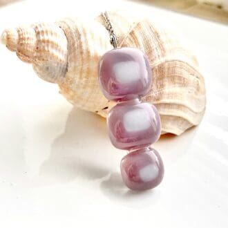 Three lilac and white glass pieces fused together vertically to create a necklace.