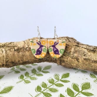 Arch shaped dangle earrings with a hare print in plum and green.