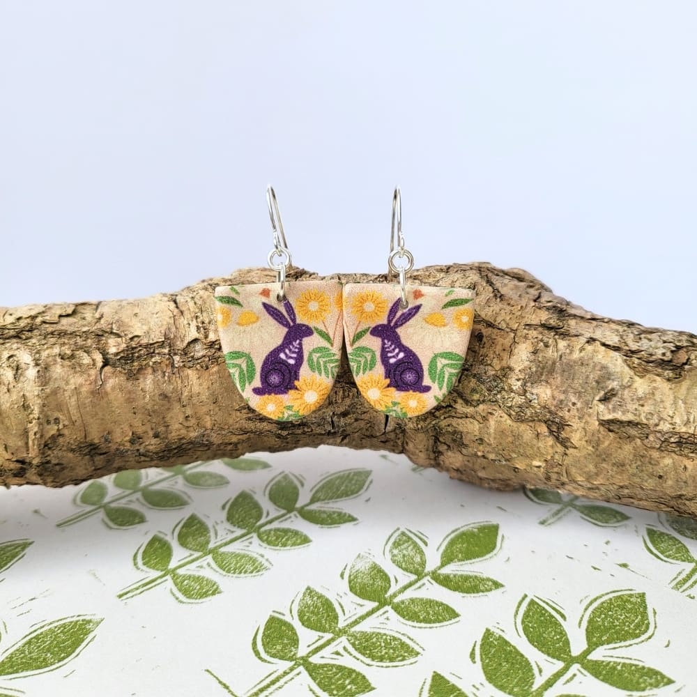 Arch shaped dangle earrings with a hare print in plum and green.