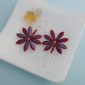 Handmade Daisy earrings in bright red with a metallic blue leaf pattern