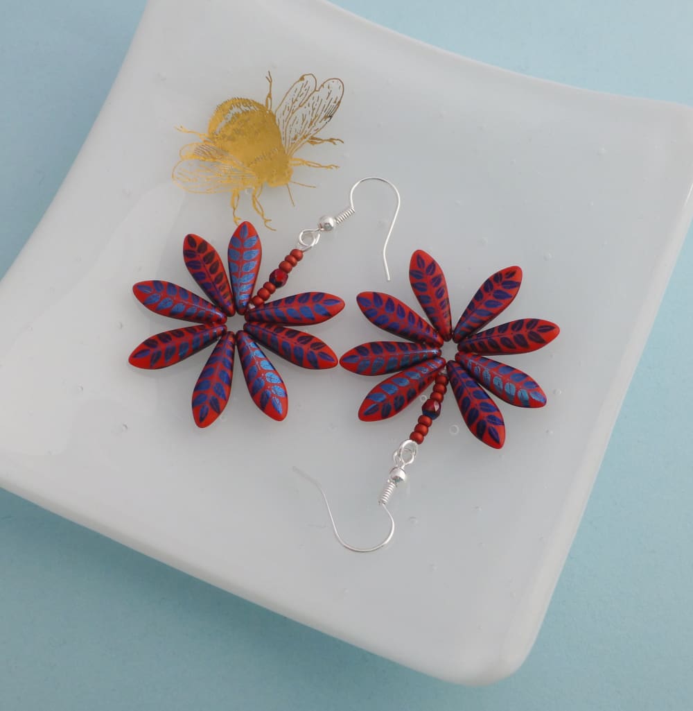 Handmade Daisy earrings in bright red with a metallic blue leaf pattern