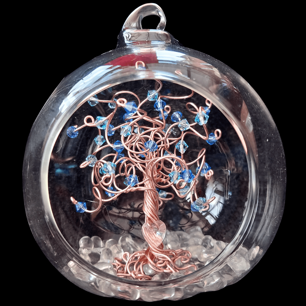 8cm open fronted glass bauble with a rose gold wire tree set inside it on a glass pebble base. The tree has a mix of sapphire and aquamarine crystals on the branches.