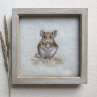A handmade needle felted wool picture of a wood mouse. The mouse is sat upright and facing forward on a cream wool background and in a natural wood frame.