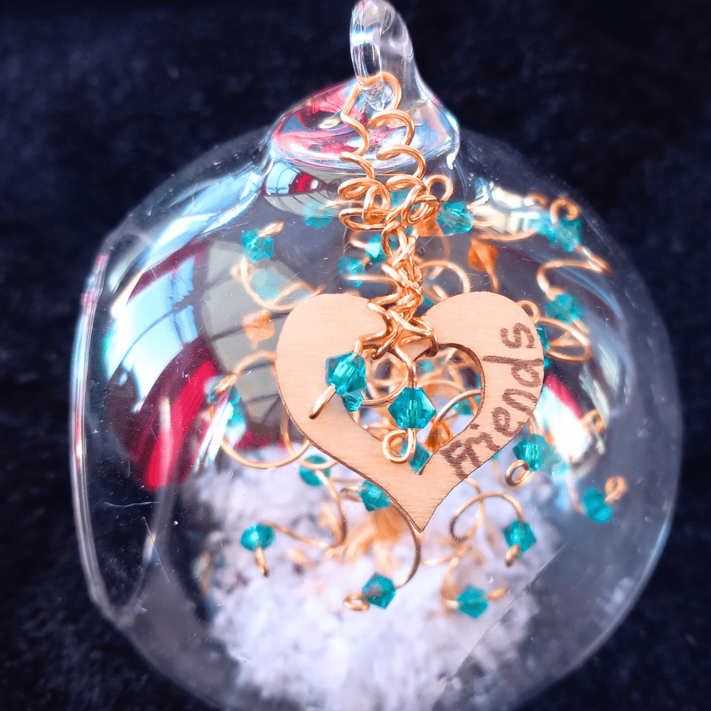 8cm glass bauble decorated with a wooden heart charm that is handwritten. The hear is decorated with two gold wire spirals with drup crystals in blue zircon.