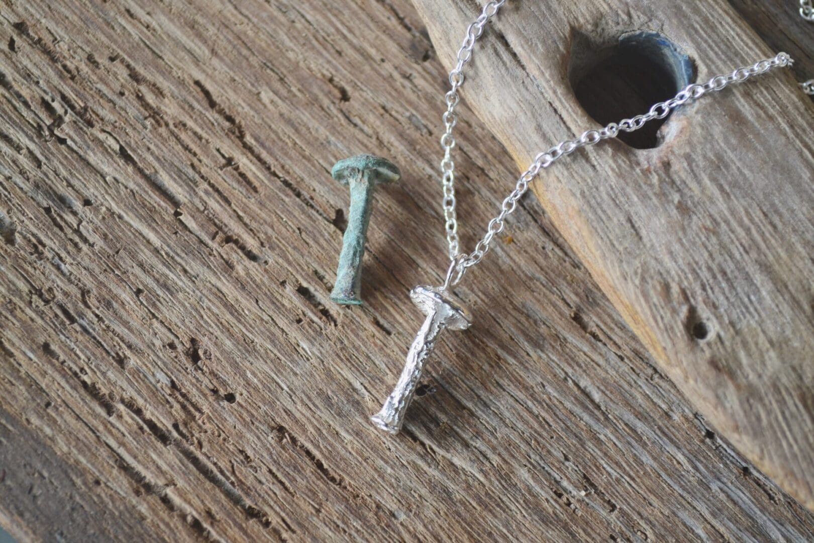 Solid silver mushroom pendant on a silver chain. Beside it is the old rivet that the pendant was cast from.