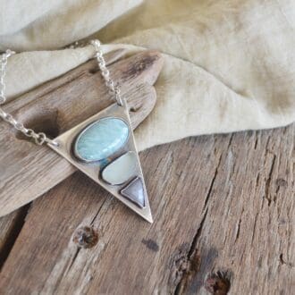 A triangular silver pendant with amazonite, sea glass and a triangular sapphire, on a silver chain attached by the top two corners