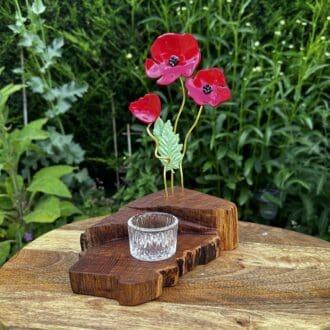 3 red resin poppies on golden wire set into a wooden base with different levels.