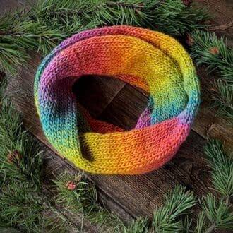 Knitted infinity loop scarf in softly colour changing yarn in shades of a warm sunset